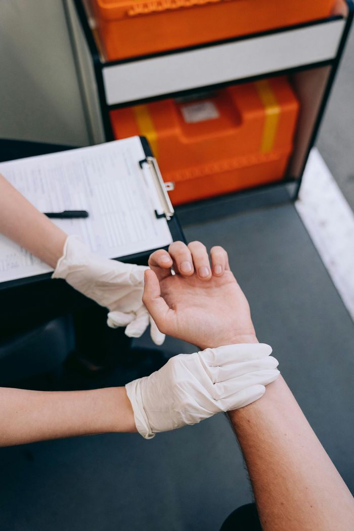 Close-up of a medic checking a patient's pulse wearing gloves.